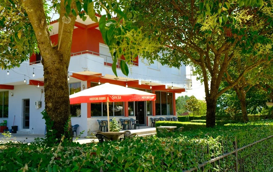 The bar-café’s terrace under the trees, with a red parasol