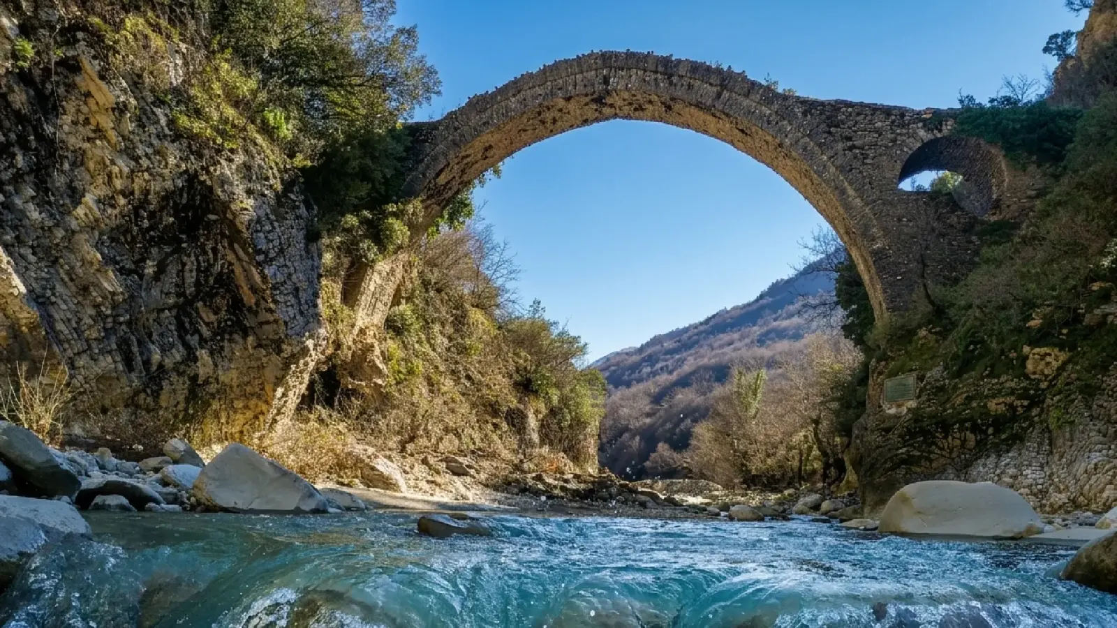 High stone arch of the Limar and Kala bridge seen from the riverbed