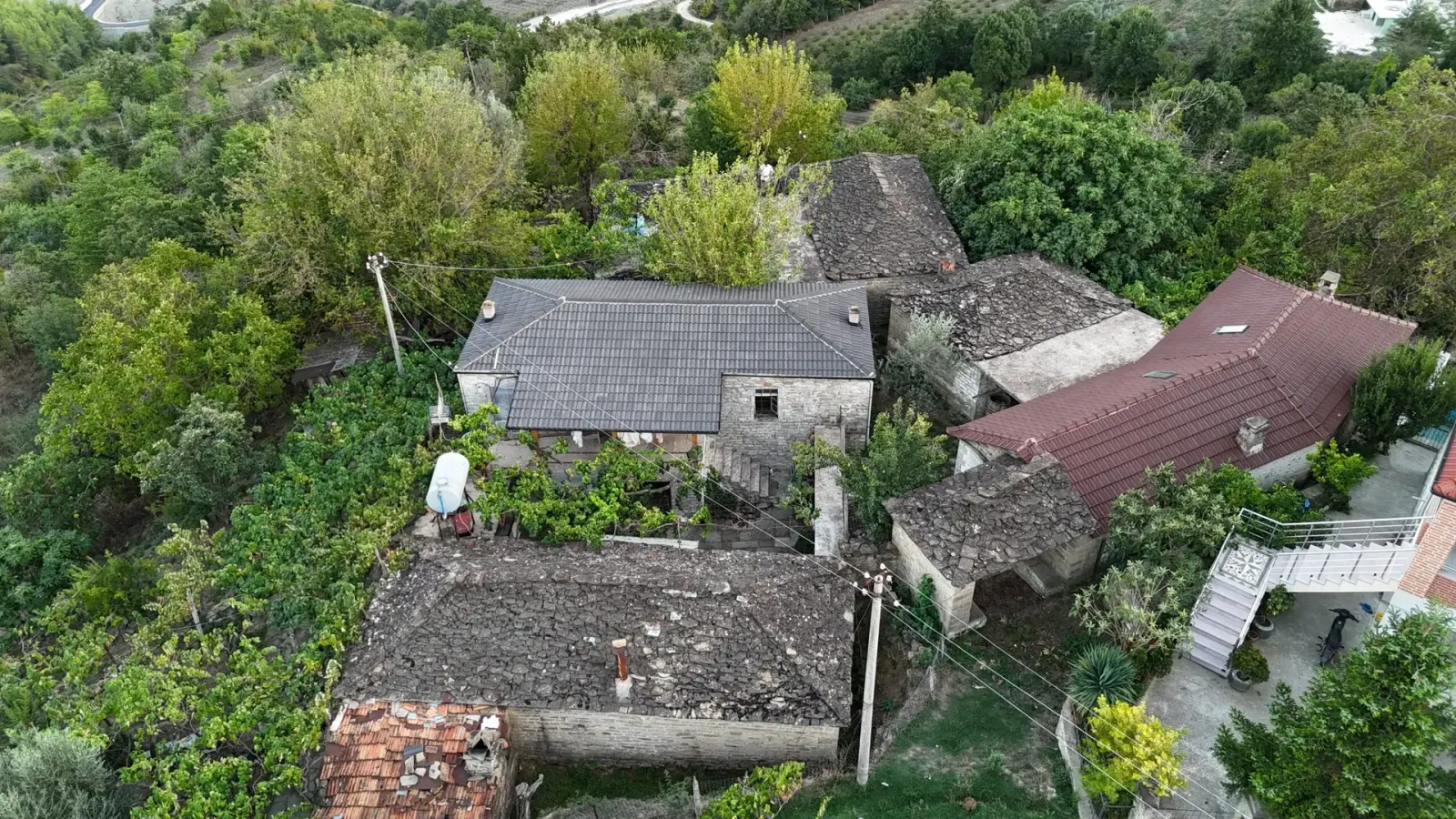 Aerial view of stone houses with slate roofs among gardens in Komarak village