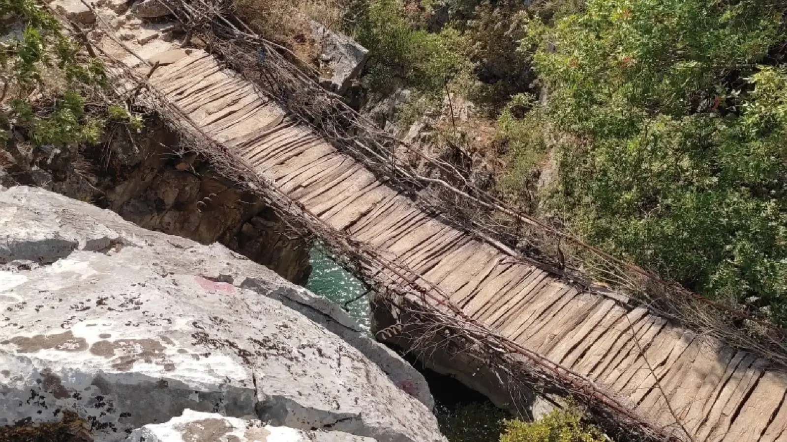 Gros plan sur le pont rustique en planches de bois de Pashtura au-dessus d'une fente rocheuse