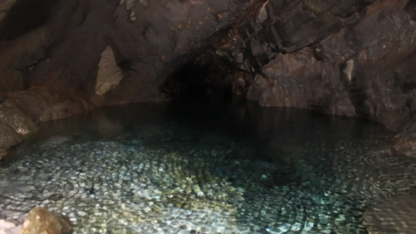 Still, clear water filling a dark chamber inside Petranik Cave