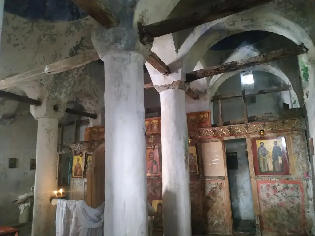 Innenraum der Nikolauskirche in Argovë mit weißen Säulen, Holzbalken und Ikonenwand