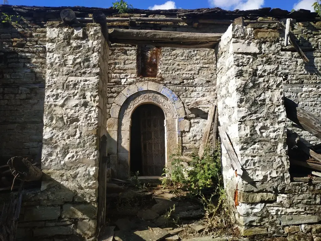 Alter steinerner Eingang der Nikolauskirche in Argovë mit gemeißeltem Bogenportal