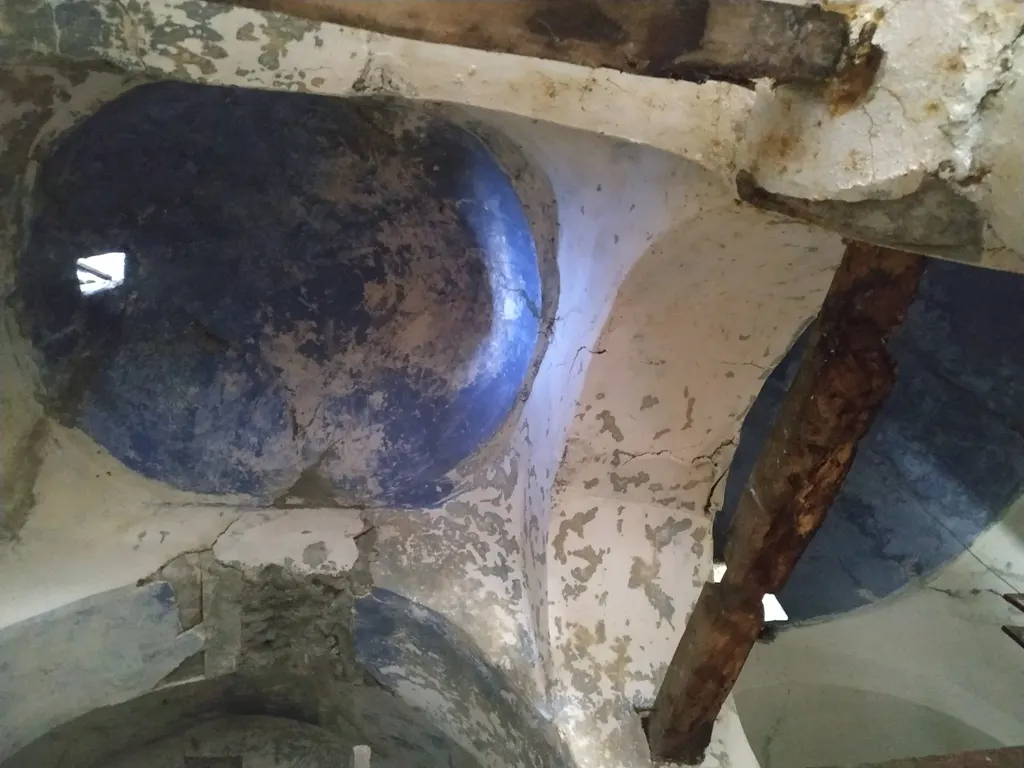 Blau bemalte Kuppeln und abgenutzte Putzgewölbe in der Nikolauskirche in Argovë, von unten gesehen