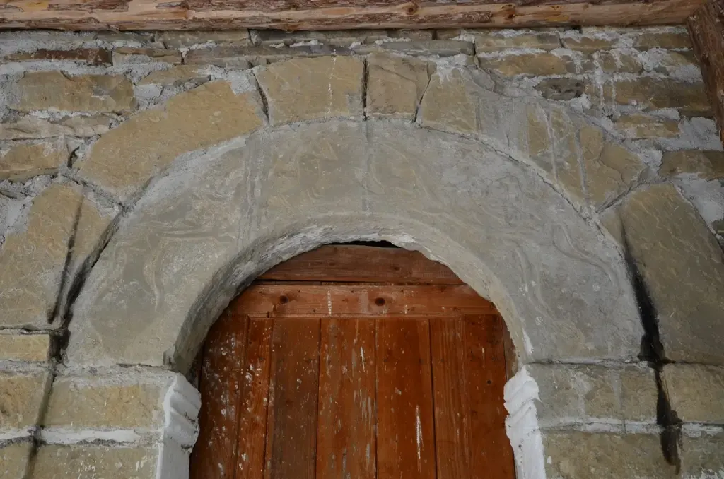Simple arc de pierre au-dessus d'une porte en bois patinée à l'église Sainte-Kyriaki à Grabovë