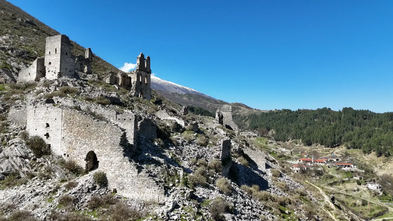 Torres de piedra y muros fortificados de Sarajet e Ali Bej Këlcyra con una cumbre nevada detrás