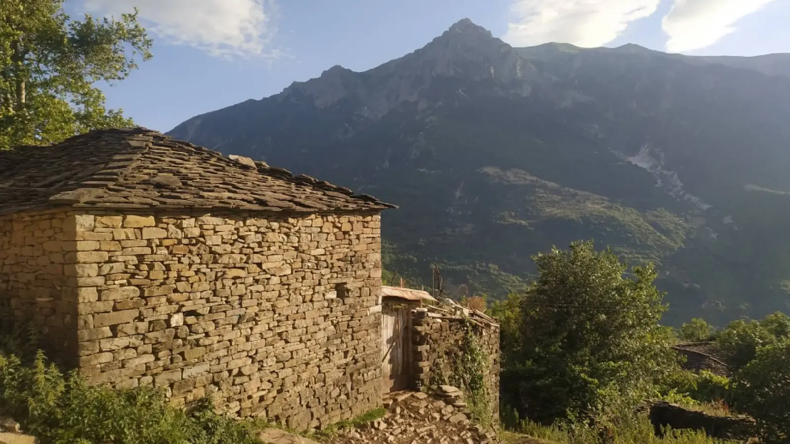 Casa in pietra con tetto in lastre nel villaggio di Leskaj sotto una ripida cresta montuosa