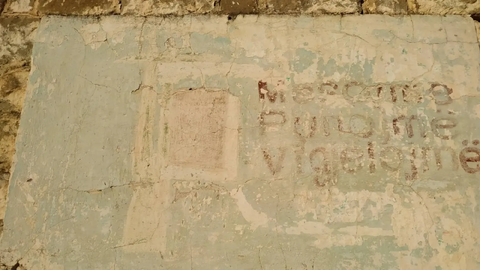 Verblasste gemalte Schrift an einer alten verputzten Wand im Dorf Mërtinj