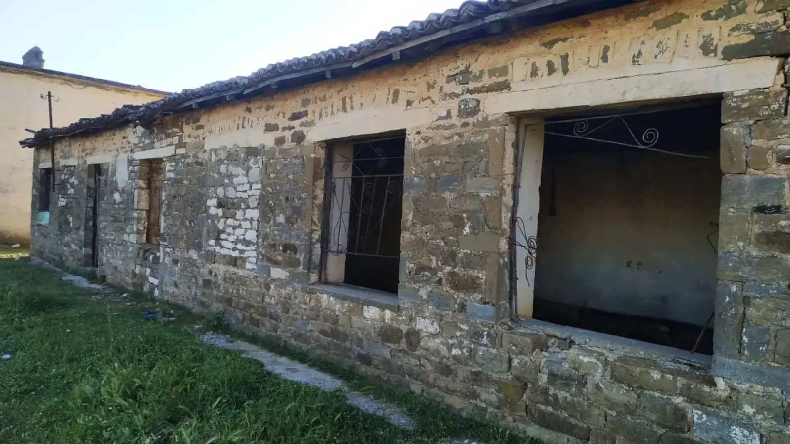 Long bâtiment en pierre abandonné aux fenêtres béantes et au toit de tuiles à Tolar